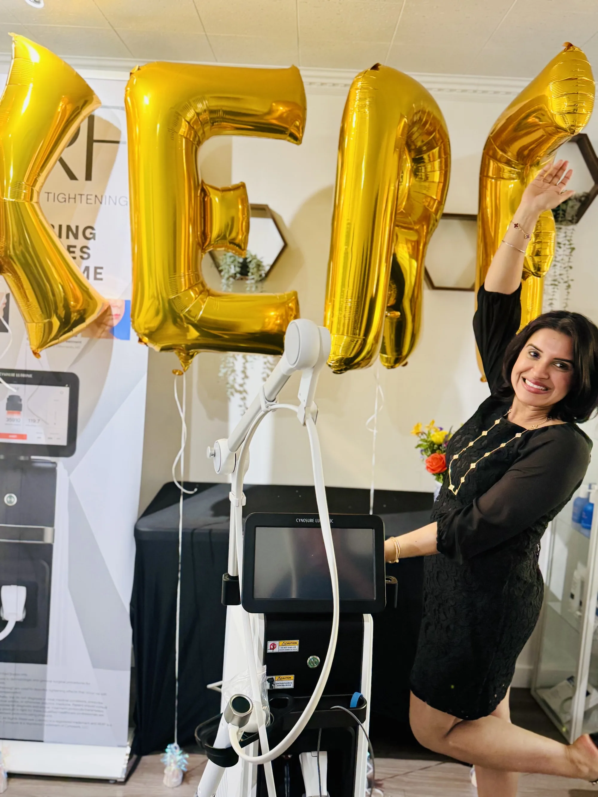 Dr. Inderpreet Sanghera posing beside the XERF device under gold balloons spelling XERF