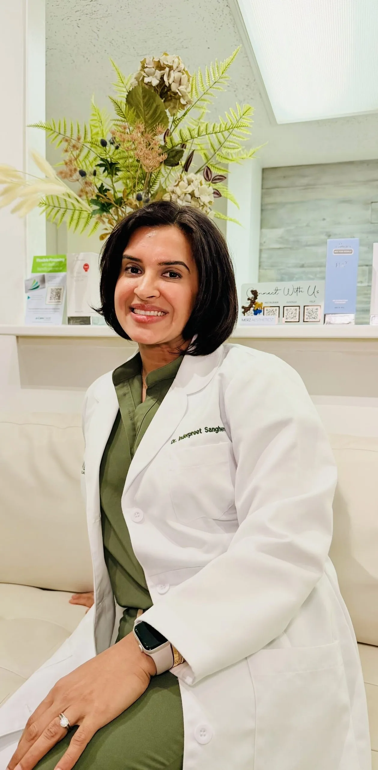Dr. Inderpreet Sanghera in a white coat, seated in the clinic