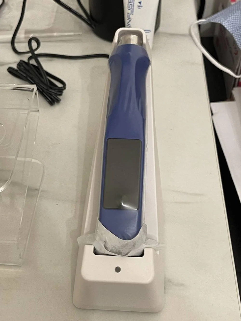 A SkinPen microneedling device resting in its stand