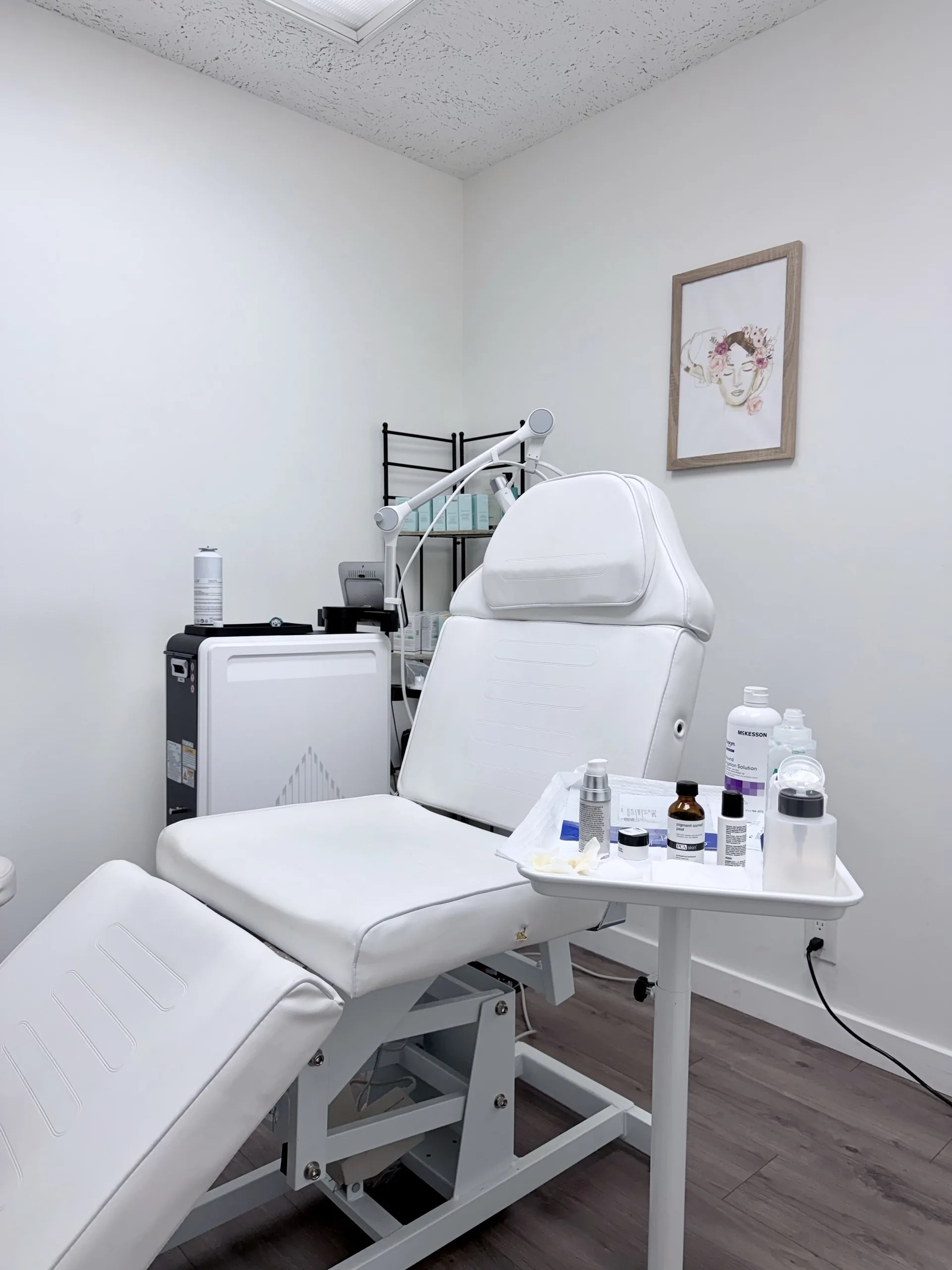 A white treatment chair beside a tray of skincare products in a Lotus MD treatment room