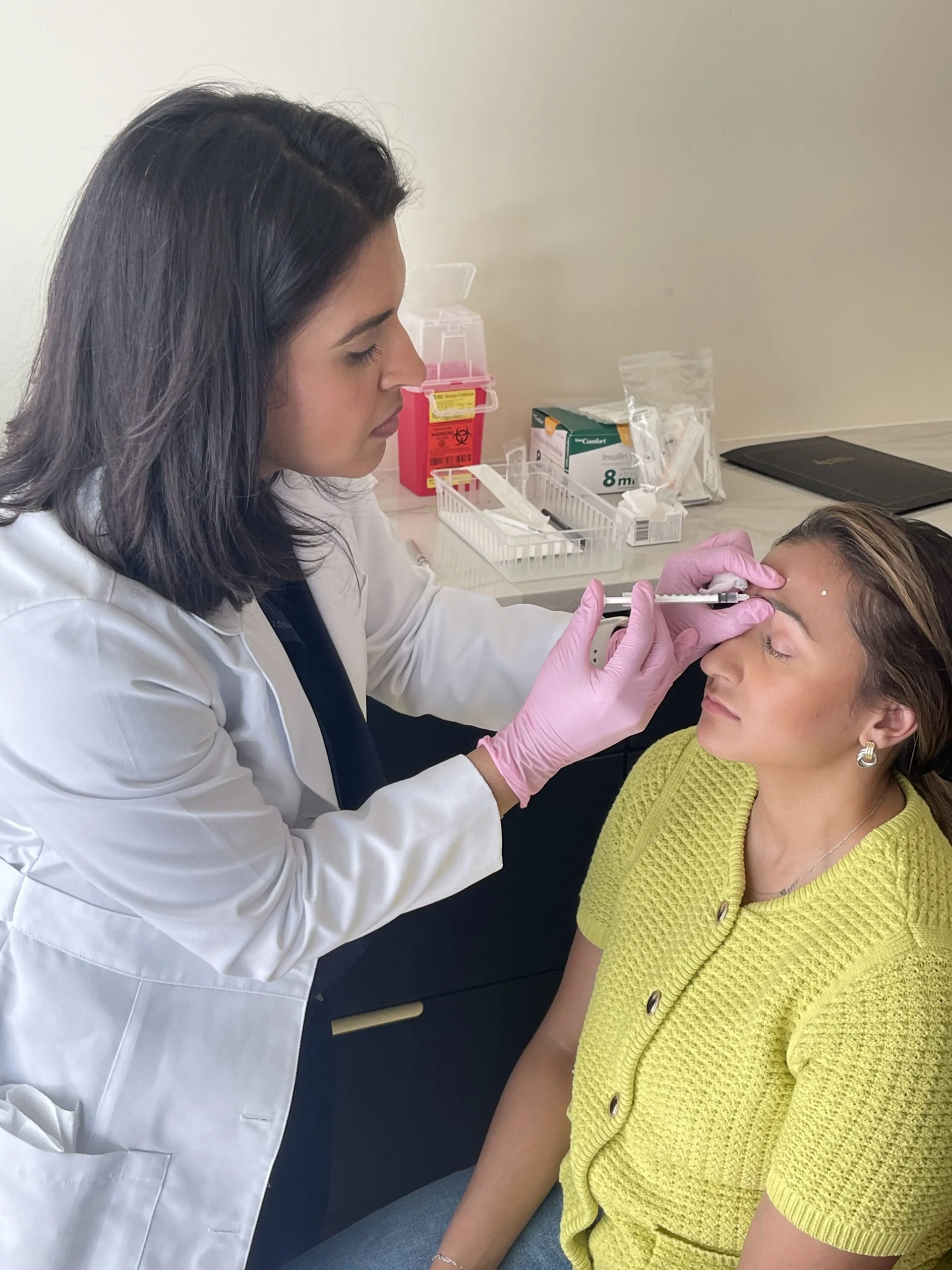 A provider giving a Botox injection to a patient's forehead
